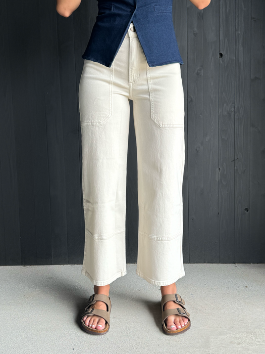 Person wearing white pants and sandals on a gray floor.