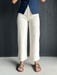 Person wearing white pants and sandals on a gray floor.
